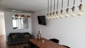 Una sala de estar moderna con una mesa de comedor de madera, sillas de cuero y un televisor de pantalla plana montado en la pared.
