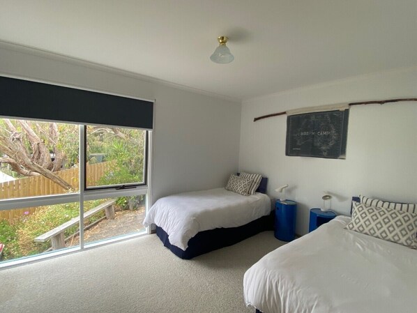 A bedroom with two beds, a window, a ceiling fan, and a wall-mounted light fixture. - BEAUTIFUL BEACH HOUSE - BRILLIANT POSITION (Anglesea)