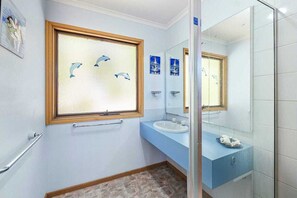 Bathroom features a sink, mirror, glass shower, and towel racks.