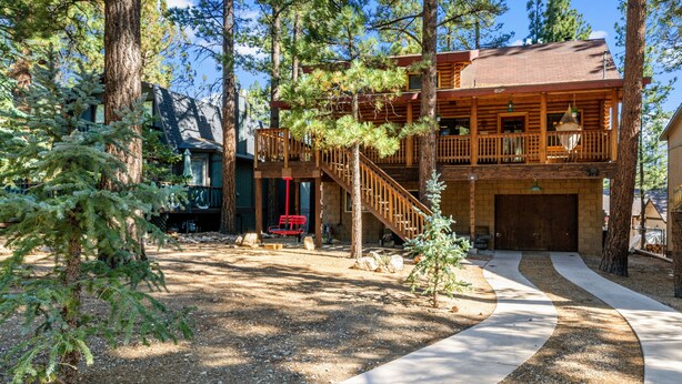A cabin with a wooden exterior, a covered porch, and a staircase leading to the upper level.
