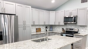 A modern kitchen with white cabinets, stainless steel appliances, granite countertops, and a built-in microwave.