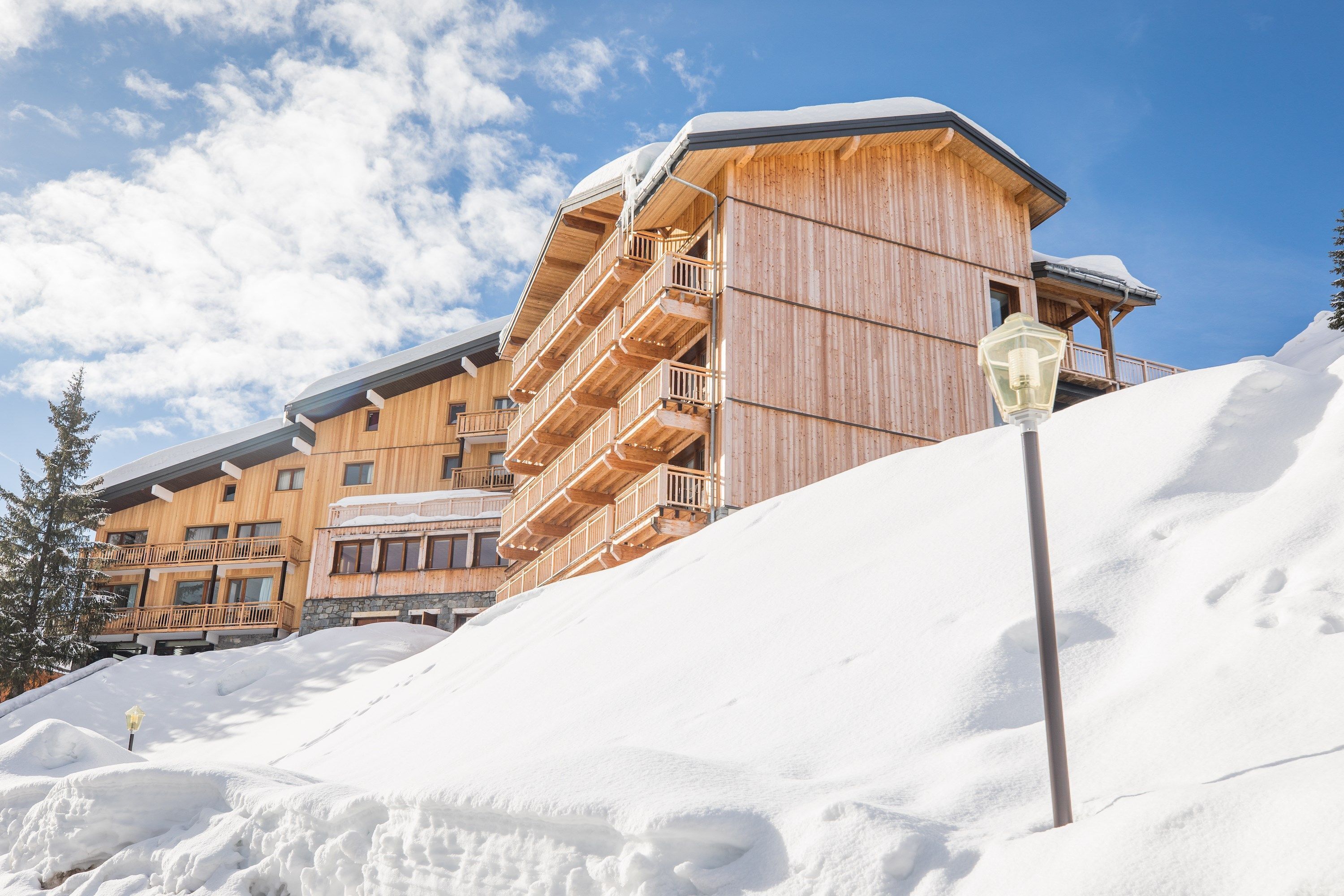 A wooden building with multiple balconies and a snow-covered slope.