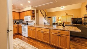 A kitchen with wooden cabinets, a white refrigerator, a microwave, and a stove. There is a staircase leading to another level. - Family-Friendly, Private 2 Acres with Stunning Views (Topton)