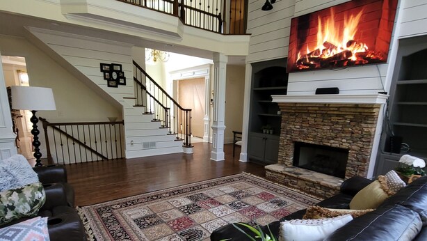 A spacious living room with a fireplace, a staircase, and a large TV. - Live in a mansion near the city, offering a resort-style setup. (Duluth)