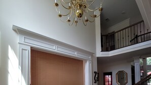 A spacious foyer with a large wooden door, a decorative floor pattern, a grand chandelier, and a staircase leading to an upper level. - Live in a mansion near the city, offering a resort-style setup. (Duluth)
