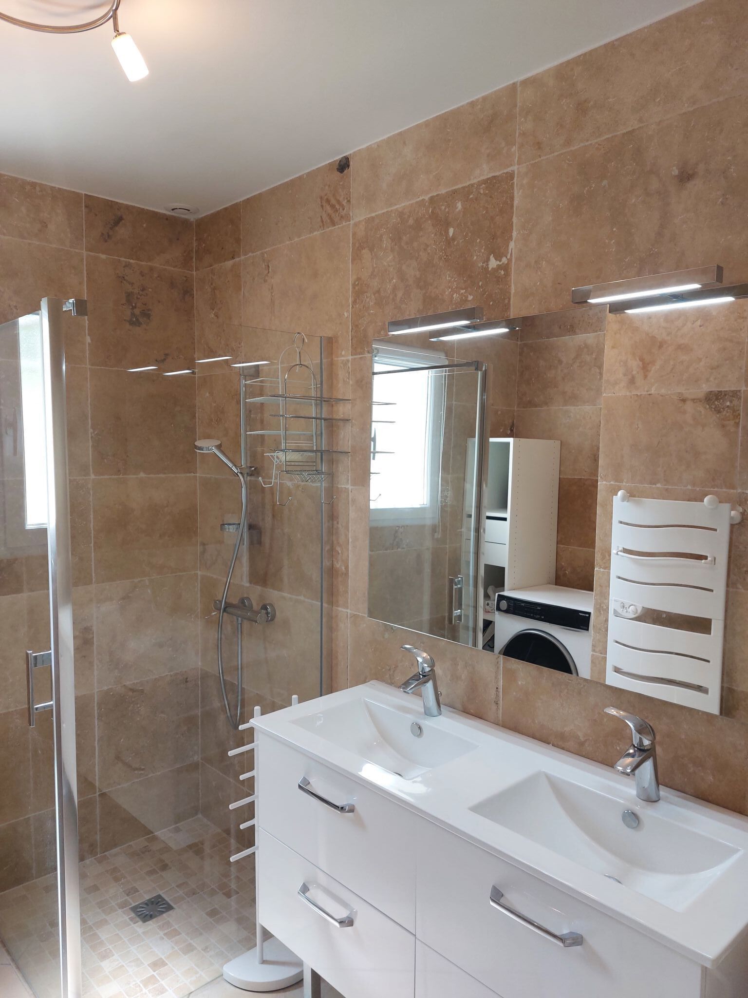A modern bathroom with a glass-enclosed shower, a white vanity with two sinks, and a large mirror.