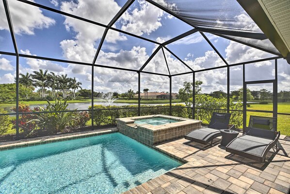 A covered outdoor pool area with a hot tub, lounge chairs, and a view of a golf course.