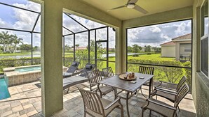 Eine überdachte Terrasse mit Pool, Gartenmöbeln und Blick auf einen Golfplatz.