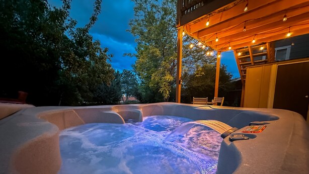 Ein Whirlpool mit einer hölzernen Pergola darüber, umgeben von Bäumen.