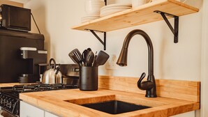 Eine Küche mit einer Holzauskładung, einem schwarzen Spülbecken, einem Herd und einem Besteckhalter.
