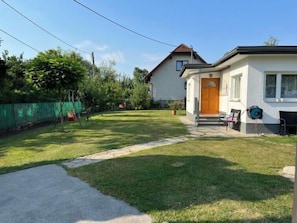 A residential property with a well-maintained lawn, a swing set, and a house with a visible front door and windows.