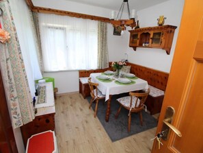 A dining area with a wooden table set for four, a bench, and a chandelier.