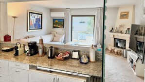 A modern kitchen with granite countertops, a coffee maker, a kettle, and a dining area with a table and chairs.