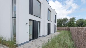 Een modern huis met twee verdiepingen, grote ramen en een verharde oprit.