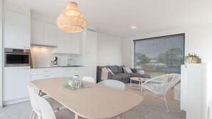 Een moderne keuken met witte kastjes, een inbouwoven en een hangende lamp.