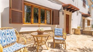 A patio with wicker furniture, a stone table, and a potted plant. - Pintor Beach House by Interhome (Port Pollença)
