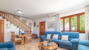 A living room with a blue sofa, wooden coffee table, and a staircase. - Pintor Beach House by Interhome (Port Pollença)