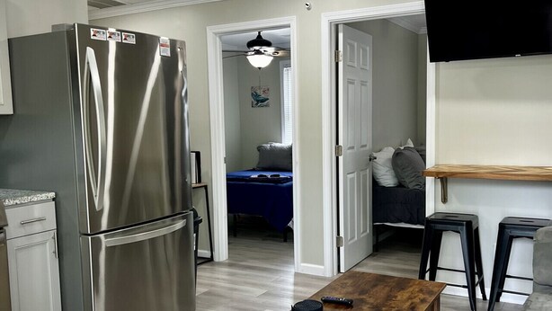 A compact kitchen with a stainless steel refrigerator, a wooden coffee table, and a grey sofa. - GOTL Strip Suite #2- Sunset Vacation Rentals (Geneva)