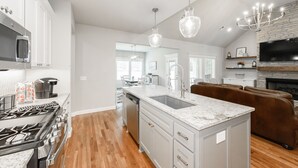 A modern kitchen with a central island, stainless steel appliances, and a fireplace. - Executive Stay, Modern Farmhouse Perfect Location. Garage Parking. (Broken Arrow)
