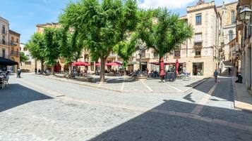 A cobblestone square with outdoor seating, trees, and historic buildings.