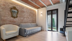 A modern living room with a brick wall, a large mirror, and a staircase.