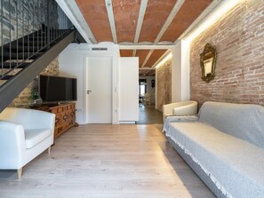Una sala moderna con una escalera, un televisor y una pared de ladrillo.