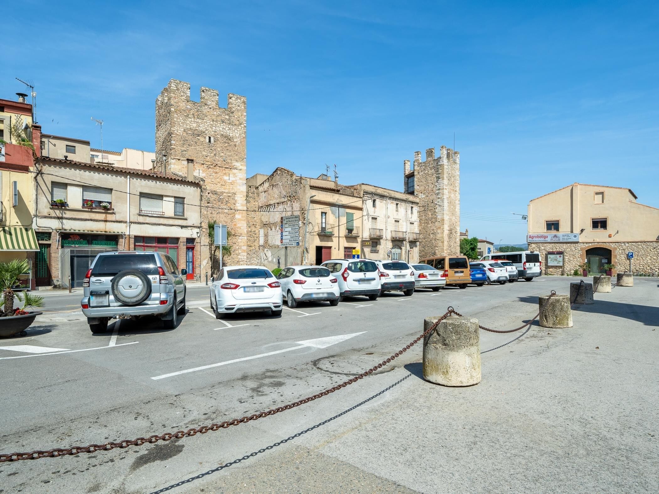 Una strada con auto parcheggiate, un castello e edifici con negozi.