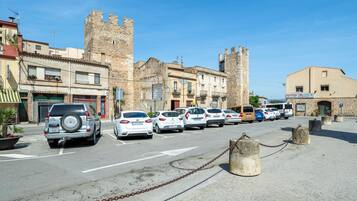 Una strada con auto parcheggiate, un castello e edifici con negozi.
