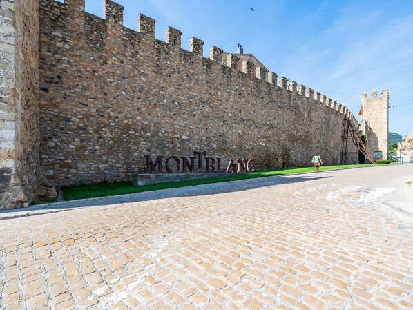 Une rue pavée, bordée d’un mur de pierres et sur laquelle on peut lire l’inscription « MONBLANC ».