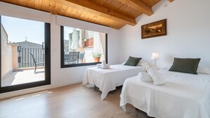 Une chambre avec deux lits, un plafond en bois, une grande fenêtre et une vue sur l’extérieur.