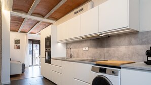 Une cuisine moderne avec des meubles blancs, un lave-linge encastré et un plan de travail en bois.