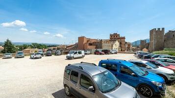 Un estacionamiento con varios automóviles y una estructura que recuerda a un castillo al fondo.