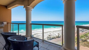Ein Balkon mit Korbstühlen, Blick auf den Strand und einen klaren Himmel.