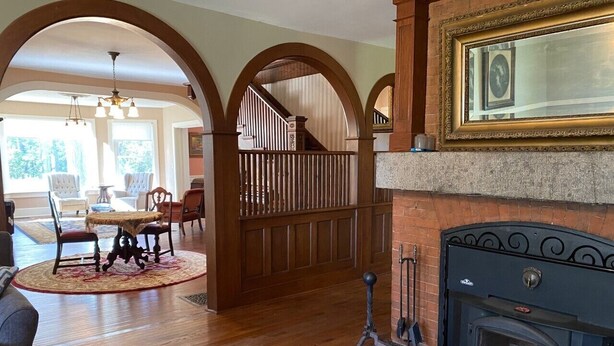 A spacious living room with hardwood floors, a fireplace, and a dining area with a round table and chairs.
