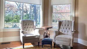 A room with two upholstered chairs, a small round table, and a patterned rug.
