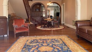 A spacious living room with a large rug, a red chair, a brown sofa, and a staircase leading to another level.
