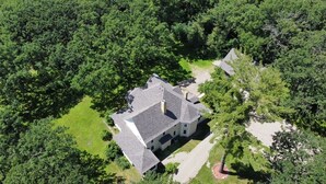 An aerial view of a house surrounded by dense trees.