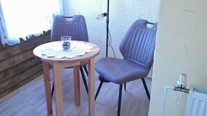 Ein Zimmer mit Holzbalken, ausgestattet mit einem runden Tisch, zwei Stühlen, einem Glas Wasser und einer Heizung.