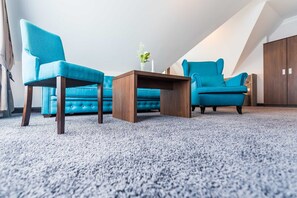 A room with a blue sofa, two matching armchairs, a wooden coffee table, and a vase with flowers.