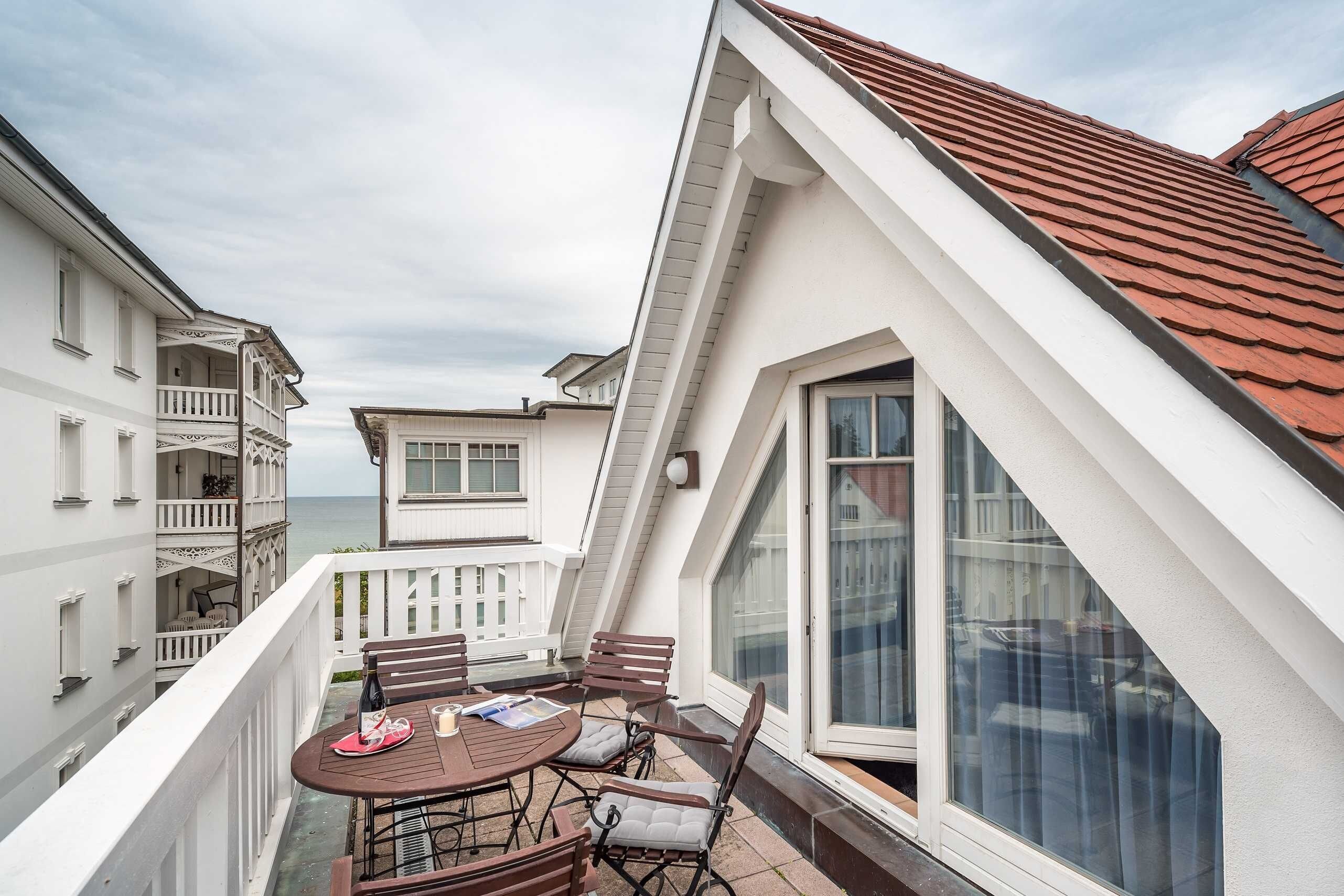 A balcony with a table, chairs, and a bottle.