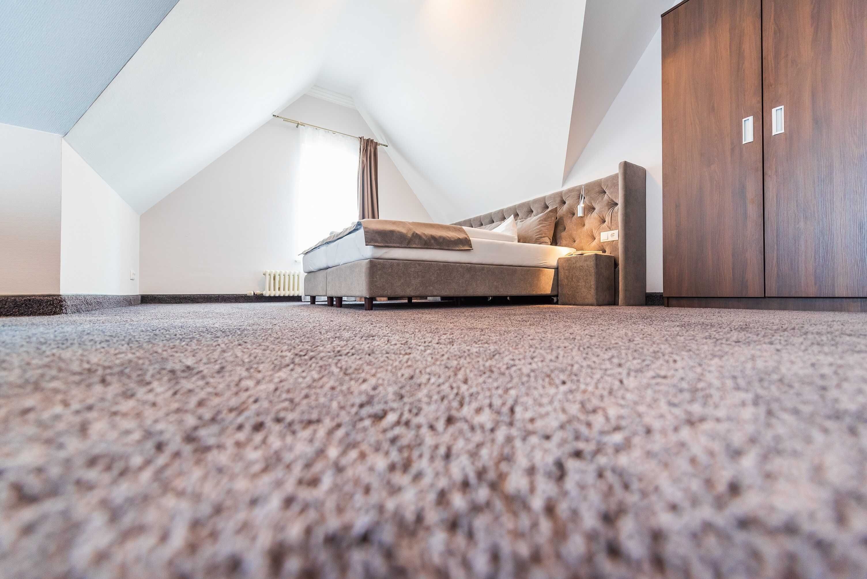 A modern loft bedroom with a high ceiling, a large bed, a wardrobe, and a radiator.