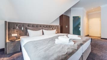 Une chambre d’hôtel moderne avec un grand lit, une table de chevet, une tête de lit et une armoire.