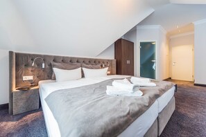 Una habitación de hotel moderna con una cama grande, una mesita de noche, un cabecero y un armario.