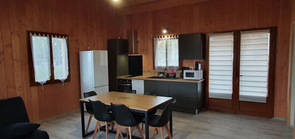 A compact kitchen with a dining area, including a table with chairs, a refrigerator, a microwave, and a sink.