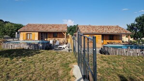 Deux cabanes en bois avec des toits en tuiles, chacune dotée d’une petite piscine et d’un espace salon extérieur.