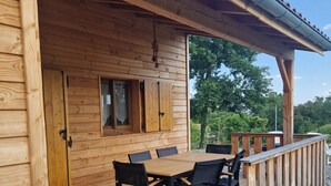 A wooden deck with a table and chairs, a wooden door, and a window.