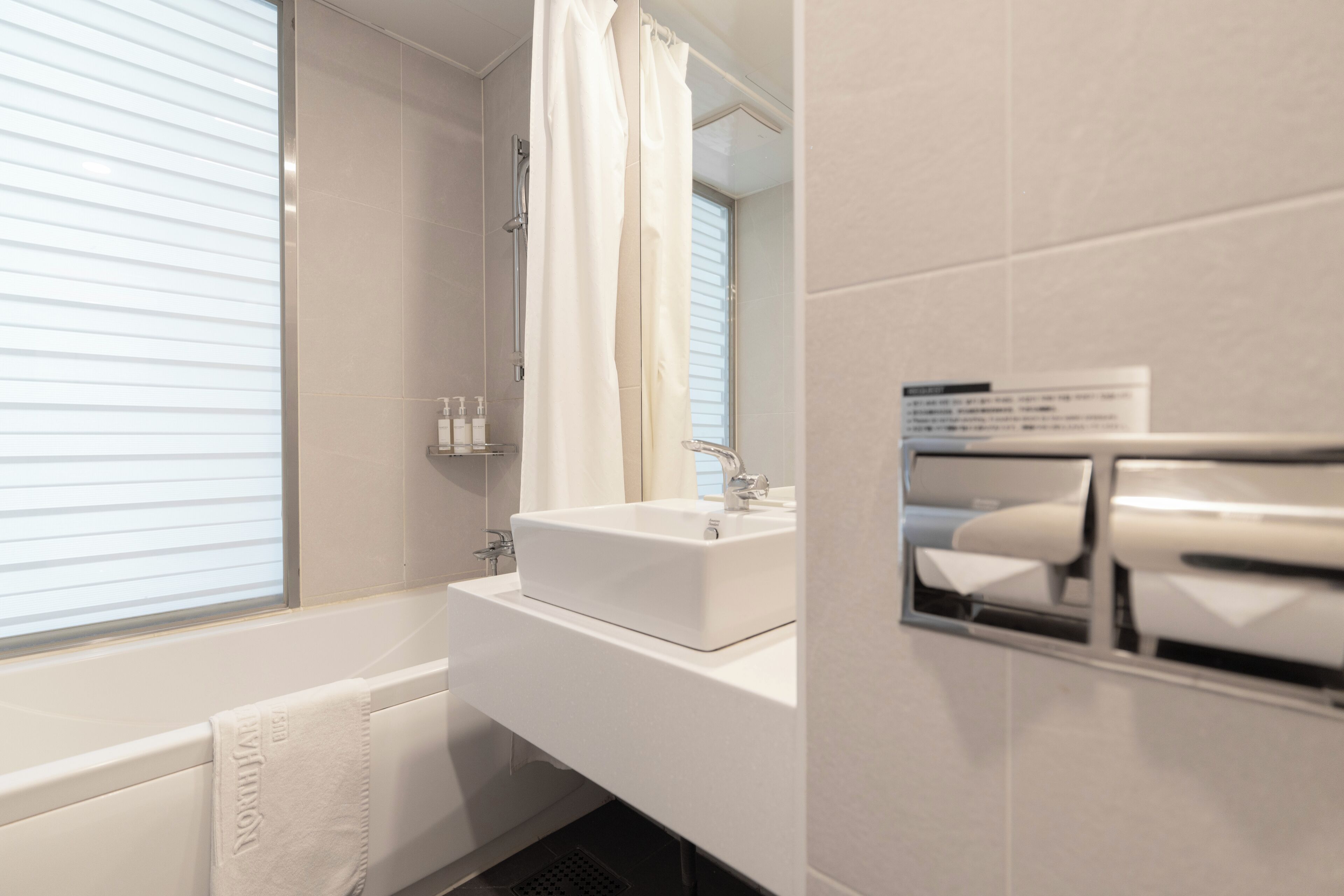 Ein modernes Badezimmer mit einem weißen Waschbecken, einer Badewanne und einer Duschvorhang.