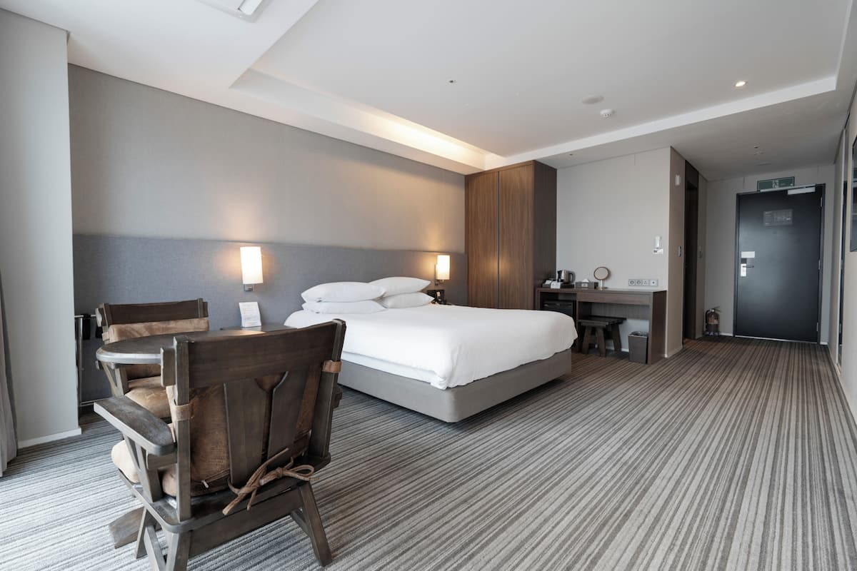 A hotel room with a large bed, a desk, a chair, and a small table.