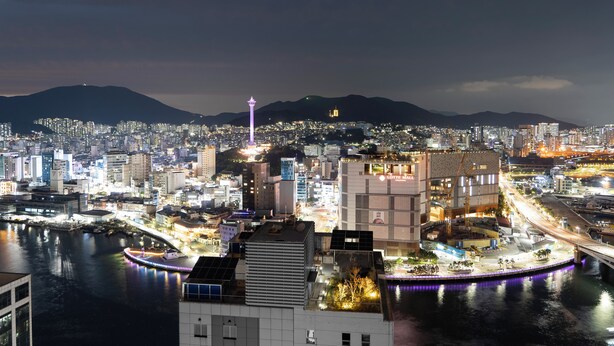 A cityscape at night with illuminated buildings, a river, and a bridge. - North Harbor Hotel Busan (Busan)