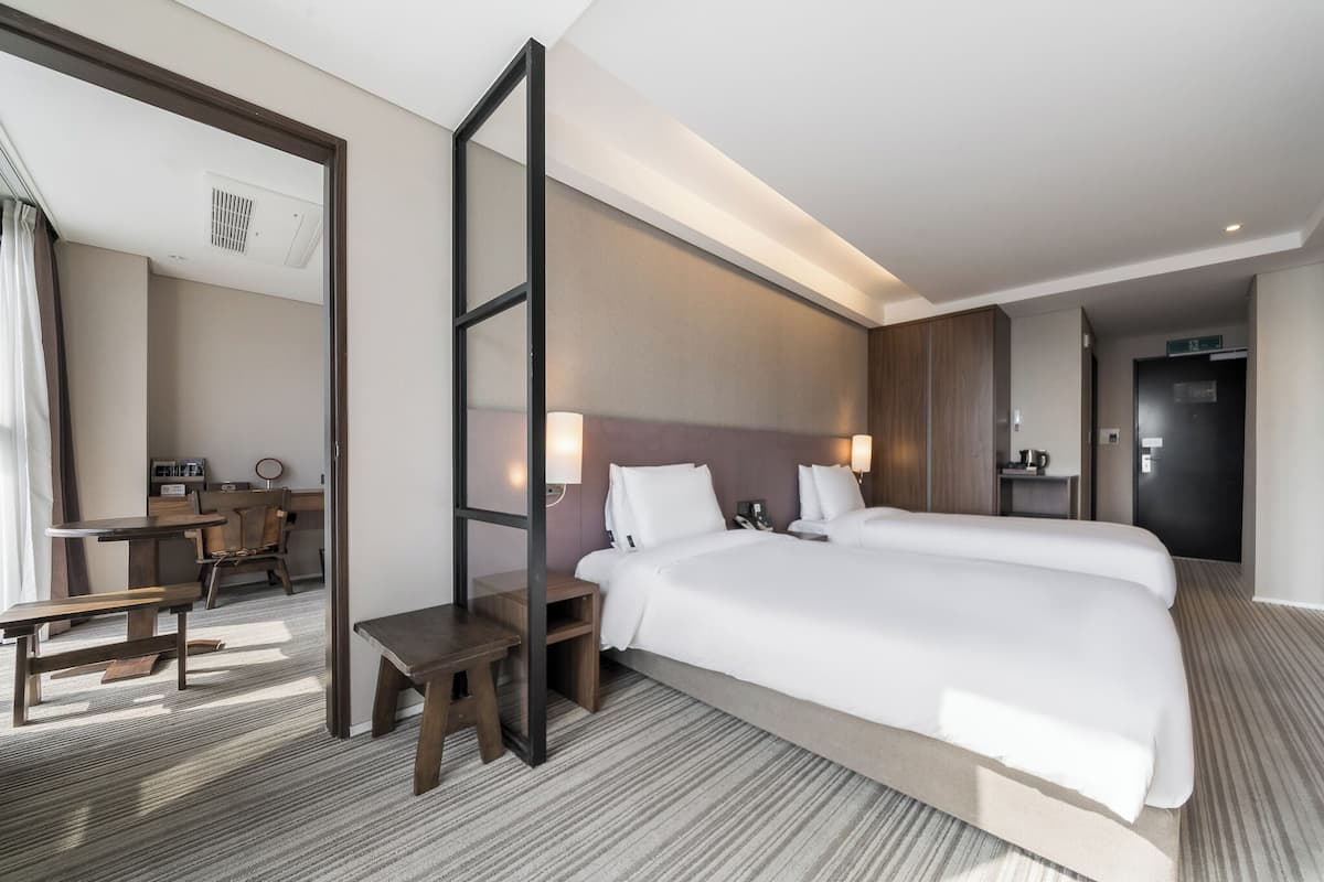 A hotel room with a large bed, a desk, a chair, and a mirror.